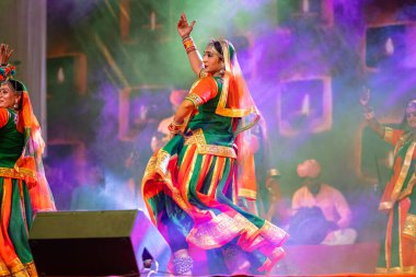 Puşkar, Rajasthan, Hindistan - Kasım 05 2022: Renkli etnik Rajasthani elbisesi içindeki itme kar fuarı sırasında genç ve güzel kadın sanatçının başıyla halk dansını sergileyen portresi.