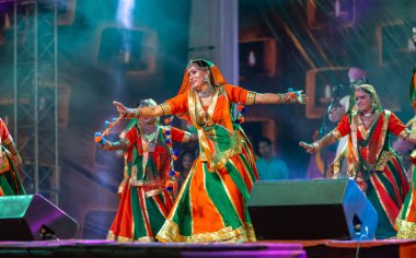 Puşkar, Rajasthan, Hindistan - Kasım 05 2022: Renkli etnik Rajasthani elbisesi içindeki itme kar fuarı sırasında genç ve güzel kadın sanatçının başıyla halk dansını sergileyen portresi.