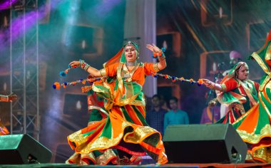 Puşkar, Rajasthan, Hindistan - Kasım 05 2022: Renkli etnik Rajasthani elbisesi içindeki itme kar fuarı sırasında genç ve güzel kadın sanatçının başıyla halk dansını sergileyen portresi.