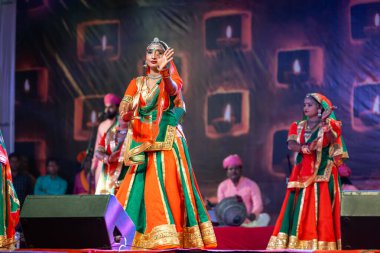 Puşkar, Rajasthan, Hindistan - Kasım 05 2022: Renkli etnik Rajasthani elbisesi içindeki itme kar fuarı sırasında genç ve güzel kadın sanatçının başıyla halk dansını sergileyen portresi.