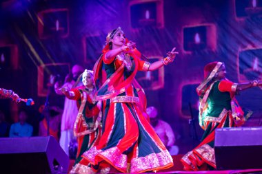 Puşkar, Rajasthan, Hindistan - Kasım 05 2022: Renkli etnik Rajasthani elbisesi içindeki itme kar fuarı sırasında genç ve güzel kadın sanatçının başıyla halk dansını sergileyen portresi.