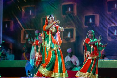 Puşkar, Rajasthan, Hindistan - Kasım 05 2022: Renkli etnik Rajasthani elbisesi içindeki itme kar fuarı sırasında genç ve güzel kadın sanatçının başıyla halk dansını sergileyen portresi.