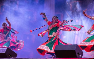 Puşkar, Rajasthan, Hindistan - Kasım 05 2022: Renkli etnik Rajasthani elbisesi içindeki itme kar fuarı sırasında genç ve güzel kadın sanatçının başıyla halk dansını sergileyen portresi.