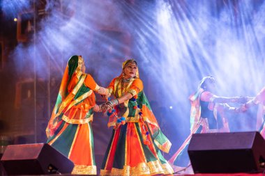 Puşkar, Rajasthan, Hindistan - Kasım 05 2022: Renkli etnik Rajasthani elbisesi içindeki itme kar fuarı sırasında genç ve güzel kadın sanatçının başıyla halk dansını sergileyen portresi.