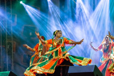 Puşkar, Rajasthan, Hindistan - Kasım 05 2022: Renkli etnik Rajasthani elbisesi içindeki itme kar fuarı sırasında genç ve güzel kadın sanatçının başıyla halk dansını sergileyen portresi.