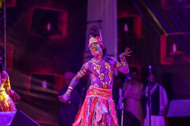 Puşkar, Rajasthan, Hindistan - Kasım 06 2022: Hintli erkek sanatçı rajasthani folk dansı yapıyor Sahariya kabilesi boyalı yüzlü ve renkli boyalı vücutlu, açık renk elbiseli.