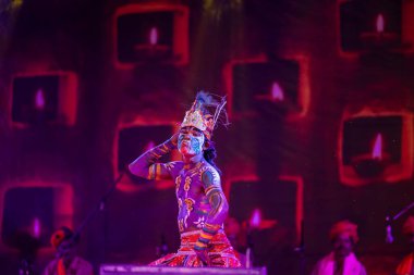 Puşkar, Rajasthan, Hindistan - Kasım 06 2022: Hintli erkek sanatçı rajasthani folk dansı yapıyor Sahariya kabilesi boyalı yüzlü ve renkli boyalı vücutlu, açık renk elbiseli.