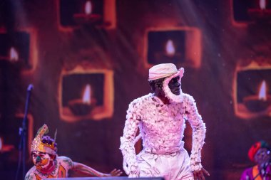 Puşkar, Rajasthan, Hindistan - Kasım 06 2022: Hintli erkek sanatçı rajasthani folk dansı yapıyor Sahariya kabilesi boyalı yüzlü ve renkli boyalı vücutlu, açık renk elbiseli.