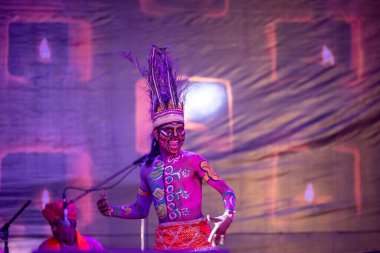 Puşkar, Rajasthan, Hindistan - Kasım 06 2022: Hintli erkek sanatçı rajasthani folk dansı yapıyor Sahariya kabilesi boyalı yüzlü ve renkli boyalı vücutlu, açık renk elbiseli.