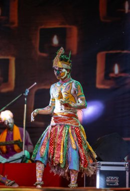 Puşkar, Rajasthan, Hindistan - Kasım 06 2022: Hintli erkek sanatçı rajasthani folk dansı yapıyor Sahariya kabilesi boyalı yüzlü ve renkli boyalı vücutlu, açık renk elbiseli.