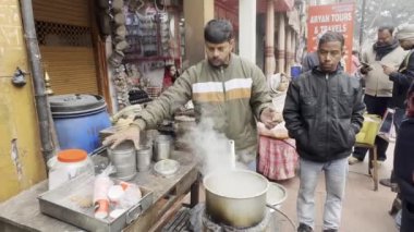 Varanasi, Uttar Pradesh, Hindistan - 19 Ocak 2024: Sokak Çay Dükkanı, Varanasi 'deki Assi Ghat' ta Ganj nehri kenarında çay hazırlayan bir çay satıcısının görüntüleri.