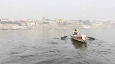 Varanasi, Uttar Pradesh, Hindistan - 20 Ocak 2024: Turistler ve yerliler sabah erken saatlerde Ganj Nehri 'nde tekne gezisinin keyfini çıkarıyorlar. Kayıkçı kutsal Ganj nehrinde ahşap kayıkla yelken açıyor..