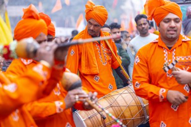 Gaziabad, Uttar Pradesh, Hindistan - 28 Ocak 2024: Yılan oynatıcı topluluğunun erkek folk sanatçıları, iskon rath yatra sırasında geleneksel kıyafetleriyle müzik aleti kullanıyorlar.