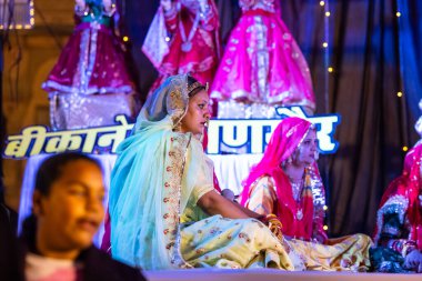 Bikaner, Rajasthan, Hindistan - 13 Ocak 2023: Geleneksel renkli rajashani kıyafetleri içinde güzel bir kadın grubu ve deve festivali sırasında sahnede kültürel gangaur pooja gösterisi.