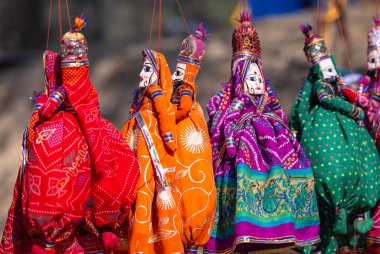 Indian colorful Rajasthani handmade Puppets and Crafts products hanging on display. Selective focus.  clipart