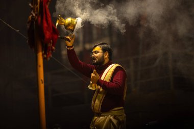 Varanasi, Uttar Pradesh, Hindistan - 18 Ocak 2024: Ganga aarti, Genç erkek rahibin portresi Dashashwamedh ghat 'ta kutsal nehir ganges akşam aarti gösterisi Hindu ayinleri ile geleneksel elbise.