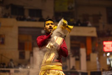 Varanasi, Uttar Pradesh, Hindistan - 18 Ocak 2024: Ganga aarti, Genç erkek rahibin portresi Dashashwamedh ghat 'ta kutsal nehir ganges akşam aarti gösterisi Hindu ayinleri ile geleneksel elbise.