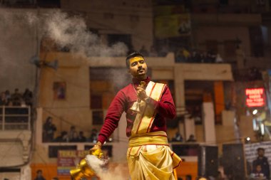 Varanasi, Uttar Pradesh, Hindistan - 18 Ocak 2024: Ganga aarti, Genç erkek rahibin portresi Dashashwamedh ghat 'ta kutsal nehir ganges akşam aarti gösterisi Hindu ayinleri ile geleneksel elbise.