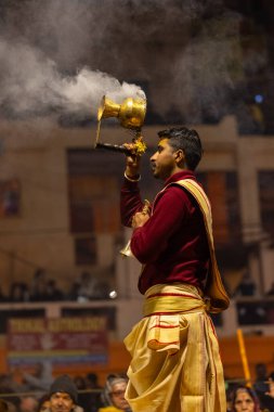 Varanasi, Uttar Pradesh, Hindistan - 18 Ocak 2024: Ganga aarti, Genç erkek rahibin portresi Dashashwamedh ghat 'ta kutsal nehir ganges akşam aarti gösterisi Hindu ayinleri ile geleneksel elbise.