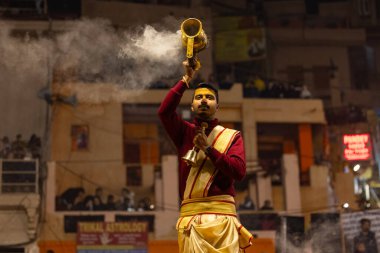 Varanasi, Uttar Pradesh, Hindistan - 18 Ocak 2024: Ganga aarti, Genç erkek rahibin portresi Dashashwamedh ghat 'ta kutsal nehir ganges akşam aarti gösterisi Hindu ayinleri ile geleneksel elbise.