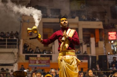 Varanasi, Uttar Pradesh, Hindistan - 18 Ocak 2024: Ganga aarti, Genç erkek rahibin portresi Dashashwamedh ghat 'ta kutsal nehir ganges akşam aarti gösterisi Hindu ayinleri ile geleneksel elbise.