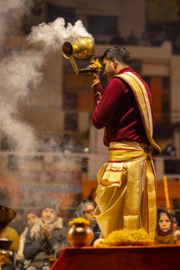 Varanasi, Uttar Pradesh, Hindistan - 18 Ocak 2024: Ganga aarti, Genç erkek rahibin portresi Dashashwamedh ghat 'ta kutsal nehir ganges akşam aarti gösterisi Hindu ayinleri ile geleneksel elbise.