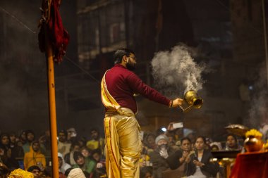 Varanasi, Uttar Pradesh, Hindistan - 18 Ocak 2024: Ganga aarti, Genç erkek rahibin portresi Dashashwamedh ghat 'ta kutsal nehir ganges akşam aarti gösterisi Hindu ayinleri ile geleneksel elbise.