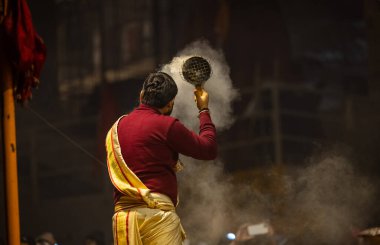 Varanasi, Uttar Pradesh, Hindistan - 18 Ocak 2024: Ganga aarti, Genç erkek rahibin portresi Dashashwamedh ghat 'ta kutsal nehir ganges akşam aarti gösterisi Hindu ayinleri ile geleneksel elbise.