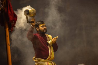 Varanasi, Uttar Pradesh, Hindistan - 18 Ocak 2024: Ganga aarti, Genç erkek rahibin portresi Dashashwamedh ghat 'ta kutsal nehir ganges akşam aarti gösterisi Hindu ayinleri ile geleneksel elbise.