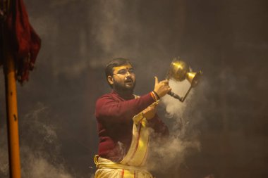 Varanasi, Uttar Pradesh, Hindistan - 18 Ocak 2024: Ganga aarti, Genç erkek rahibin portresi Dashashwamedh ghat 'ta kutsal nehir ganges akşam aarti gösterisi Hindu ayinleri ile geleneksel elbise.