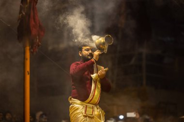 Varanasi, Uttar Pradesh, Hindistan - 18 Ocak 2024: Ganga aarti, Genç erkek rahibin portresi Dashashwamedh ghat 'ta kutsal nehir ganges akşam aarti gösterisi Hindu ayinleri ile geleneksel elbise.