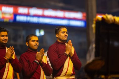 Varanasi, Uttar Pradesh, Hindistan - 18 Ocak 2024: Ganga aarti, bir grup genç erkek rahip Dashashwamedh ghat 'ta kutsal nehir çetelerini icra ediyor geleneksel Hint ayinleriyle geleneksel elbiseler içinde.