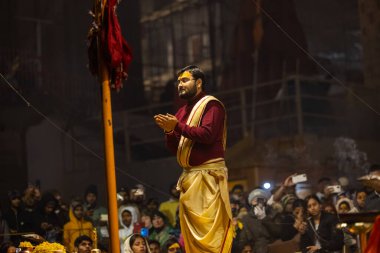 Varanasi, Uttar Pradesh, Hindistan - 18 Ocak 2024: Ganga aarti, Genç erkek rahibin portresi Dashashwamedh ghat 'ta kutsal nehir ganges akşam aarti gösterisi Hindu ayinleri ile geleneksel elbise.