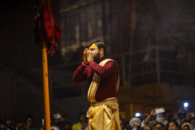Varanasi, Uttar Pradesh, Hindistan - 18 Ocak 2024: Ganga aarti, Genç erkek rahibin portresi Dashashwamedh ghat 'ta kutsal nehir ganges akşam aarti gösterisi Hindu ayinleri ile geleneksel elbise.