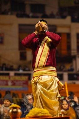 Varanasi, Uttar Pradesh, Hindistan - 18 Ocak 2024: Ganga aarti, Genç erkek rahibin portresi Dashashwamedh ghat 'ta kutsal nehir ganges akşam aarti gösterisi Hindu ayinleri ile geleneksel elbise.