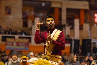 Varanasi, Uttar Pradesh, Hindistan - 18 Ocak 2024: Ganga aarti, Genç erkek rahibin portresi Dashashwamedh ghat 'ta kutsal nehir ganges akşam aarti gösterisi Hindu ayinleri ile geleneksel elbise.