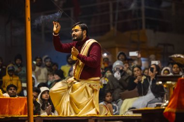 Varanasi, Uttar Pradesh, Hindistan - 18 Ocak 2024: Ganga aarti, Genç erkek rahibin portresi Dashashwamedh ghat 'ta kutsal nehir ganges akşam aarti gösterisi Hindu ayinleri ile geleneksel elbise.