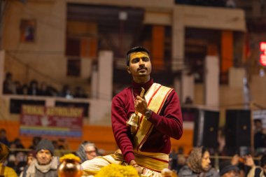 Varanasi, Uttar Pradesh, Hindistan - 18 Ocak 2024: Ganga aarti, Genç erkek rahibin portresi Dashashwamedh ghat 'ta kutsal nehir ganges akşam aarti gösterisi Hindu ayinleri ile geleneksel elbise.