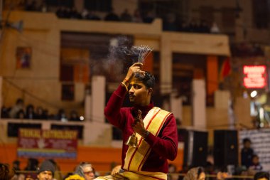 Varanasi, Uttar Pradesh, Hindistan - 18 Ocak 2024: Ganga aarti, Genç erkek rahibin portresi Dashashwamedh ghat 'ta kutsal nehir ganges akşam aarti gösterisi Hindu ayinleri ile geleneksel elbise.