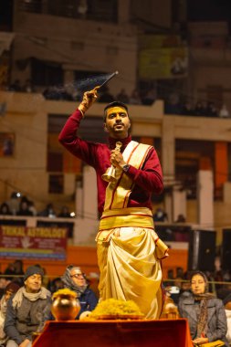 Varanasi, Uttar Pradesh, Hindistan - 18 Ocak 2024: Ganga aarti, Genç erkek rahibin portresi Dashashwamedh ghat 'ta kutsal nehir ganges akşam aarti gösterisi Hindu ayinleri ile geleneksel elbise.