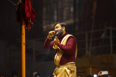 Varanasi, Uttar Pradesh, Hindistan - 18 Ocak 2024: Ganga aarti, Genç erkek rahibin portresi Dashashwamedh ghat 'ta kutsal nehir ganges akşam aarti gösterisi Hindu ayinleri ile geleneksel elbise.