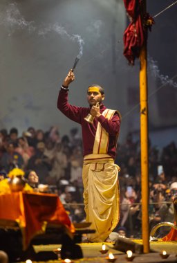 Varanasi, Uttar Pradesh, Hindistan - 18 Ocak 2024: Ganga aarti, Genç erkek rahibin portresi Dashashwamedh ghat 'ta kutsal nehir ganges akşam aarti gösterisi Hindu ayinleri ile geleneksel elbise.