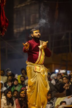 Varanasi, Uttar Pradesh, Hindistan - 18 Ocak 2024: Ganga aarti, Genç erkek rahibin portresi Dashashwamedh ghat 'ta kutsal nehir ganges akşam aarti gösterisi Hindu ayinleri ile geleneksel elbise.