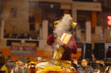 Varanasi, Uttar Pradesh, Hindistan - 18 Ocak 2024: Ganga aarti, Genç erkek rahibin portresi Dashashwamedh ghat 'ta kutsal nehir ganges akşam aarti gösterisi Hindu ayinleri ile geleneksel elbise.