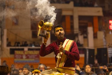 Varanasi, Uttar Pradesh, Hindistan - 18 Ocak 2024: Ganga aarti, Genç erkek rahibin portresi Dashashwamedh ghat 'ta kutsal nehir ganges akşam aarti gösterisi Hindu ayinleri ile geleneksel elbise.