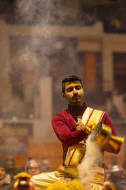 Varanasi, Uttar Pradesh, Hindistan - 18 Ocak 2024: Ganga aarti, Genç erkek rahibin portresi Dashashwamedh ghat 'ta kutsal nehir ganges akşam aarti gösterisi Hindu ayinleri ile geleneksel elbise.