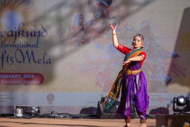 Faridabad, Haryana, Hindistan - 17 Şubat 2024: Güney Hintli bir kadın sanatçının portresi geleneksel sari ve mücevher fuarında surajkund zanaat fuarında klasik dans kuchipudi gösterisi yapıyor.