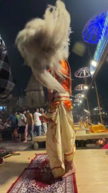 Varanasi, Uttar Pradesh, Hindistan - 22 Mart 2024: Ganga aarti, Genç erkek rahibin portresi Dashashwamedh ghat 'ta kutsal nehir ganges akşam aarti gösterisi Hindu ayinleri ile geleneksel elbise.