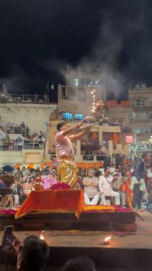 Varanasi, Uttar Pradesh, Hindistan - 20 Mart 2024: Ganga aarti, Genç erkek rahibin portresi Dashashwamedh ghat 'ta kutsal nehir ganges akşam aarti gösterisi Hindu ritüelleri ile geleneksel elbise.
