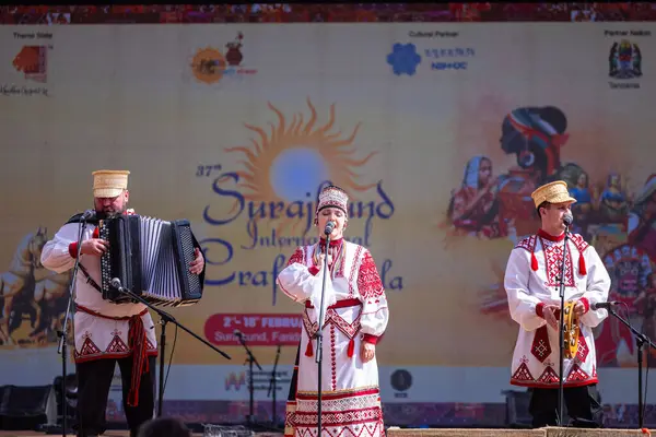 stock image Faridabad, Haryana, India - February 17 2024: Group of foreign delegates performing their cultural dance and music on stage in traditional clothes at surajkund crafts fair.